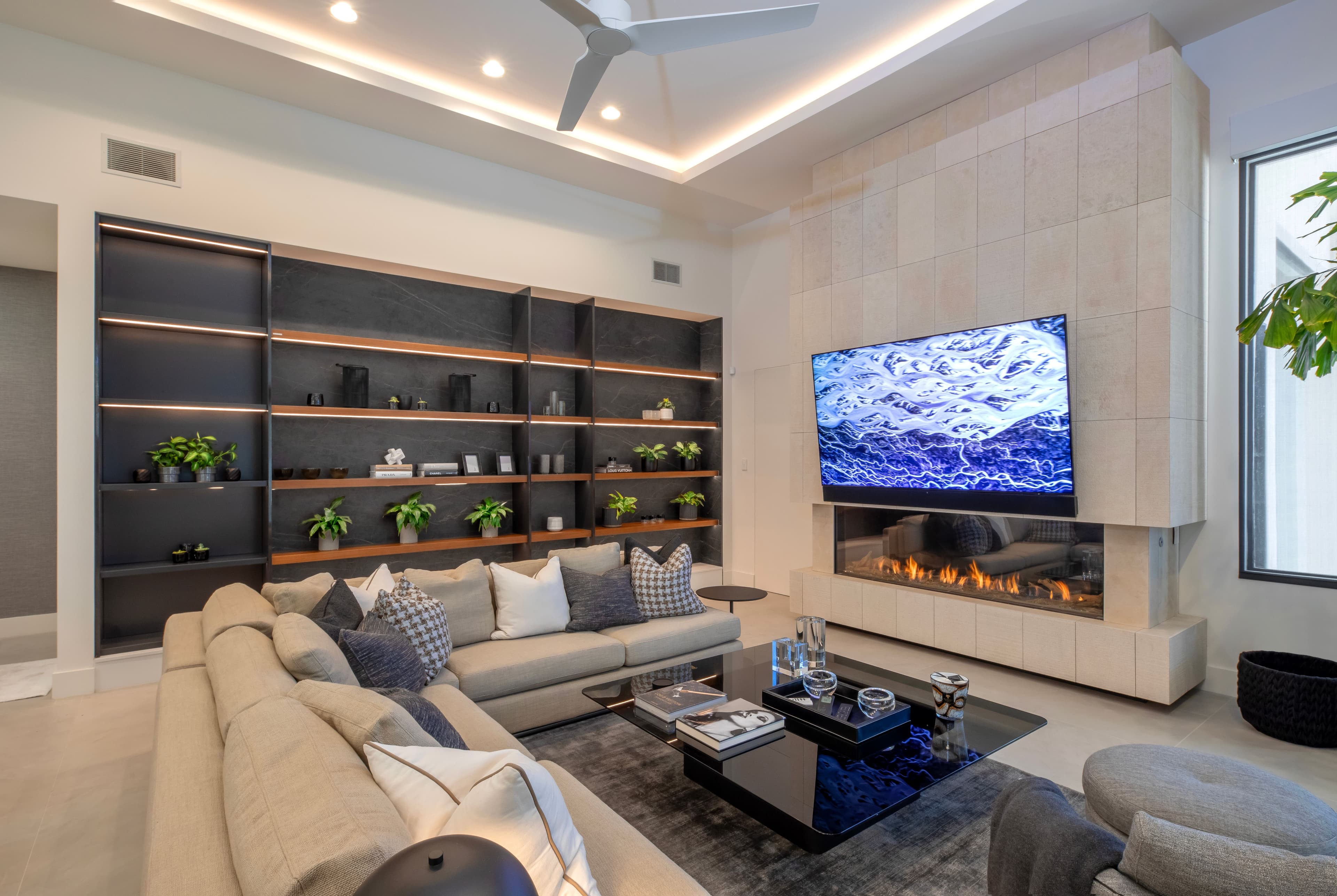 Modern living room with a cozy fireplace, large TV, custom shelving, and stylish furniture, designed by Febal Casa to highlight expert home remodeling and interior design.